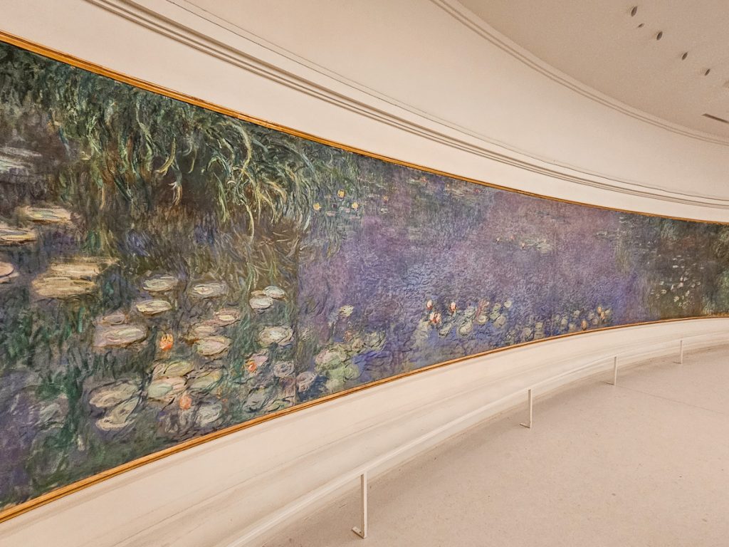 A large painting that goes across an entire wall with water lilies on the painting by Monet